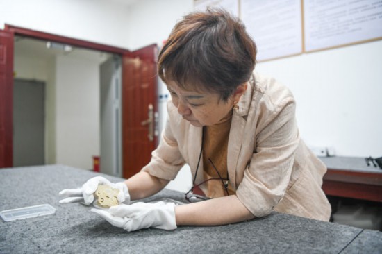 成都金沙遺址博物館副館長、中國文物學會玉器專業(yè)委員會副主任王方在鑒賞玉石上陽刻的側身人像（2024年7月10日攝）。新華社記者 王曦 攝